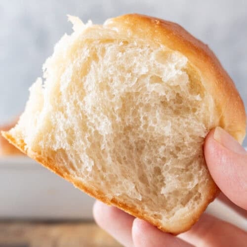 holding a soft dinner roll showing tender crumb featured image.