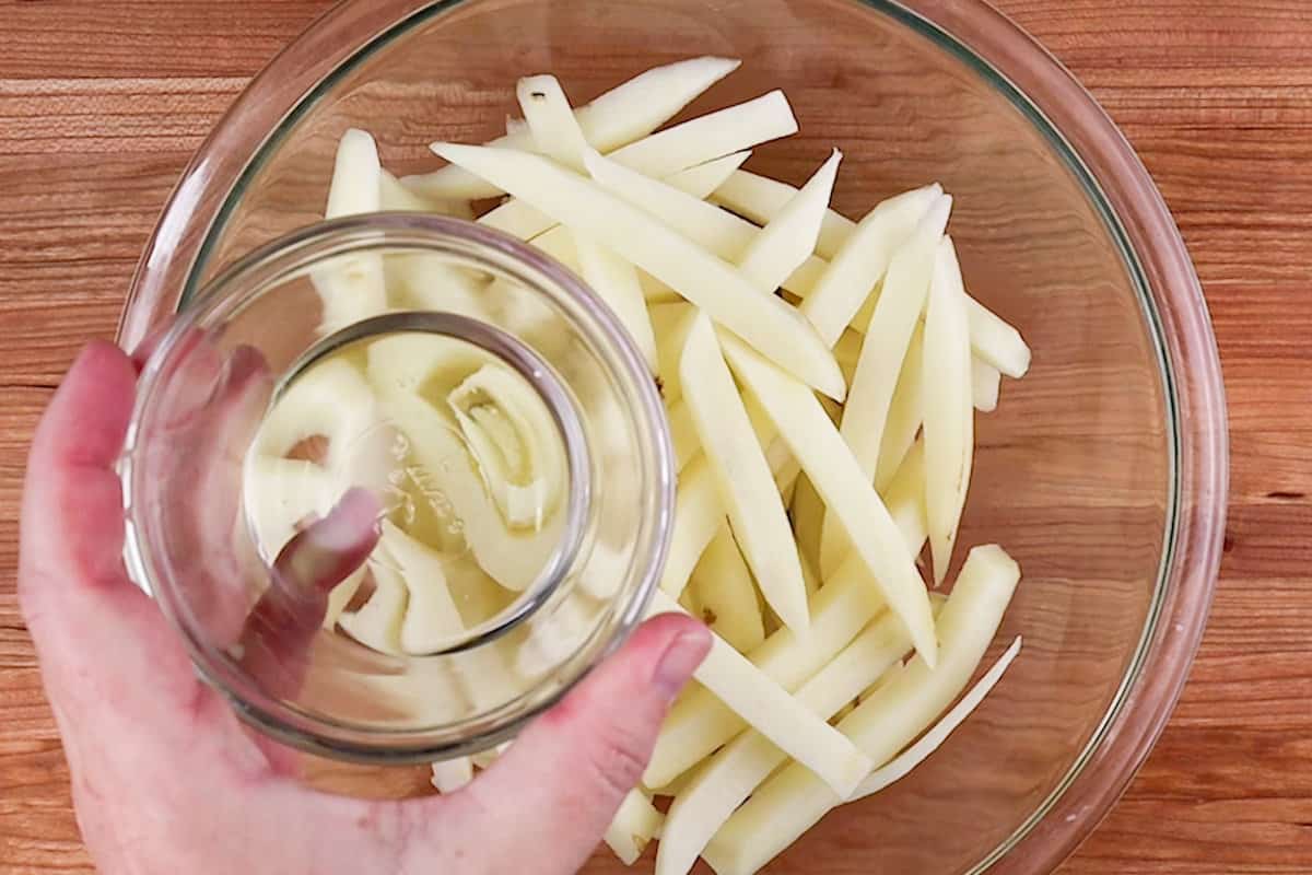 adding vegetable oil to cut potatoes