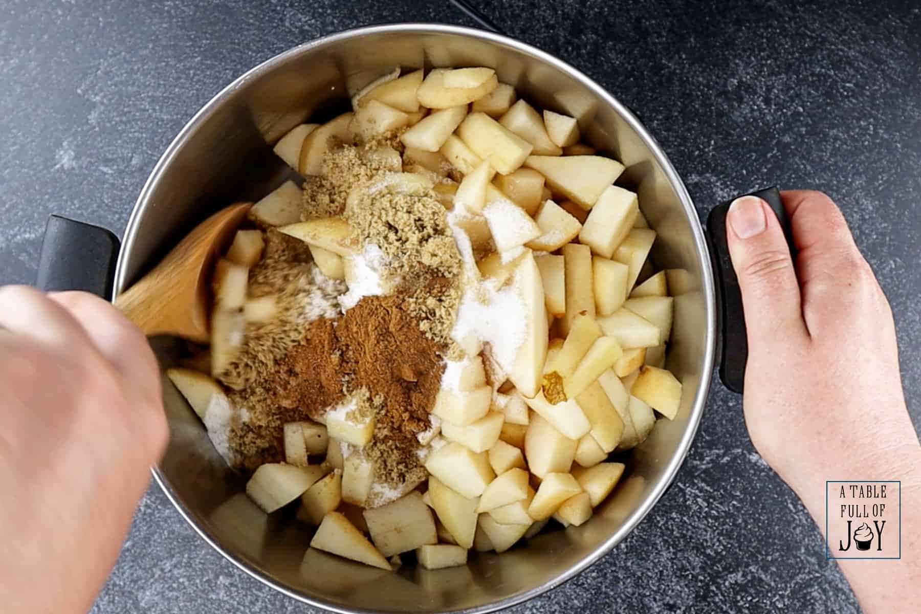 Pears being stirred with sugar and spices in  stock pot.