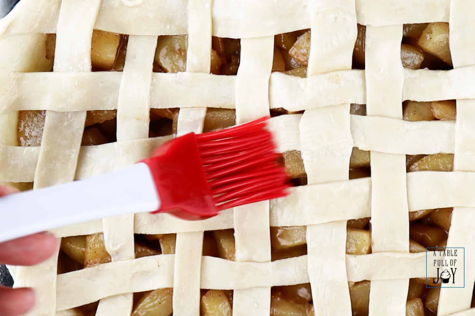 Brushing pie dough lattice with egg white.