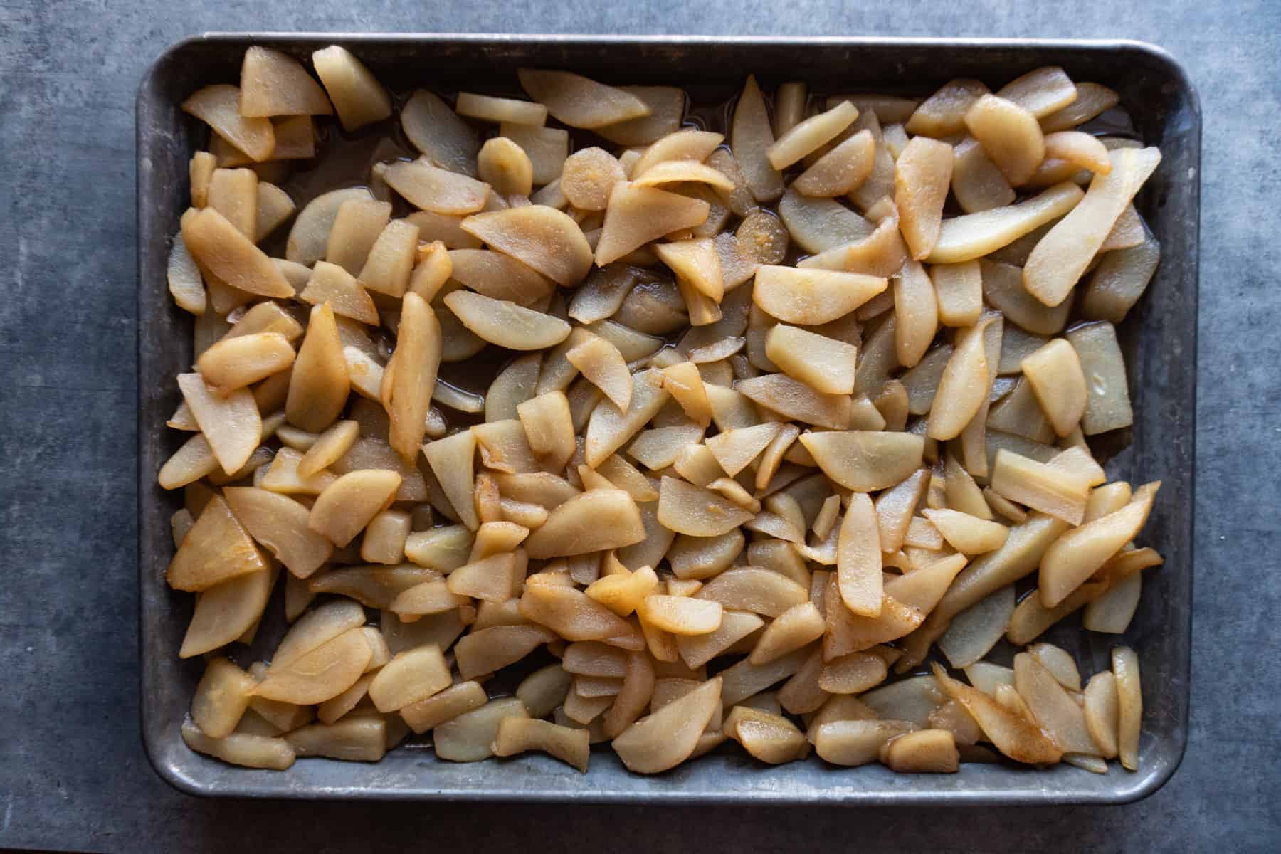 Cooked pears cooling on a baking sheet.