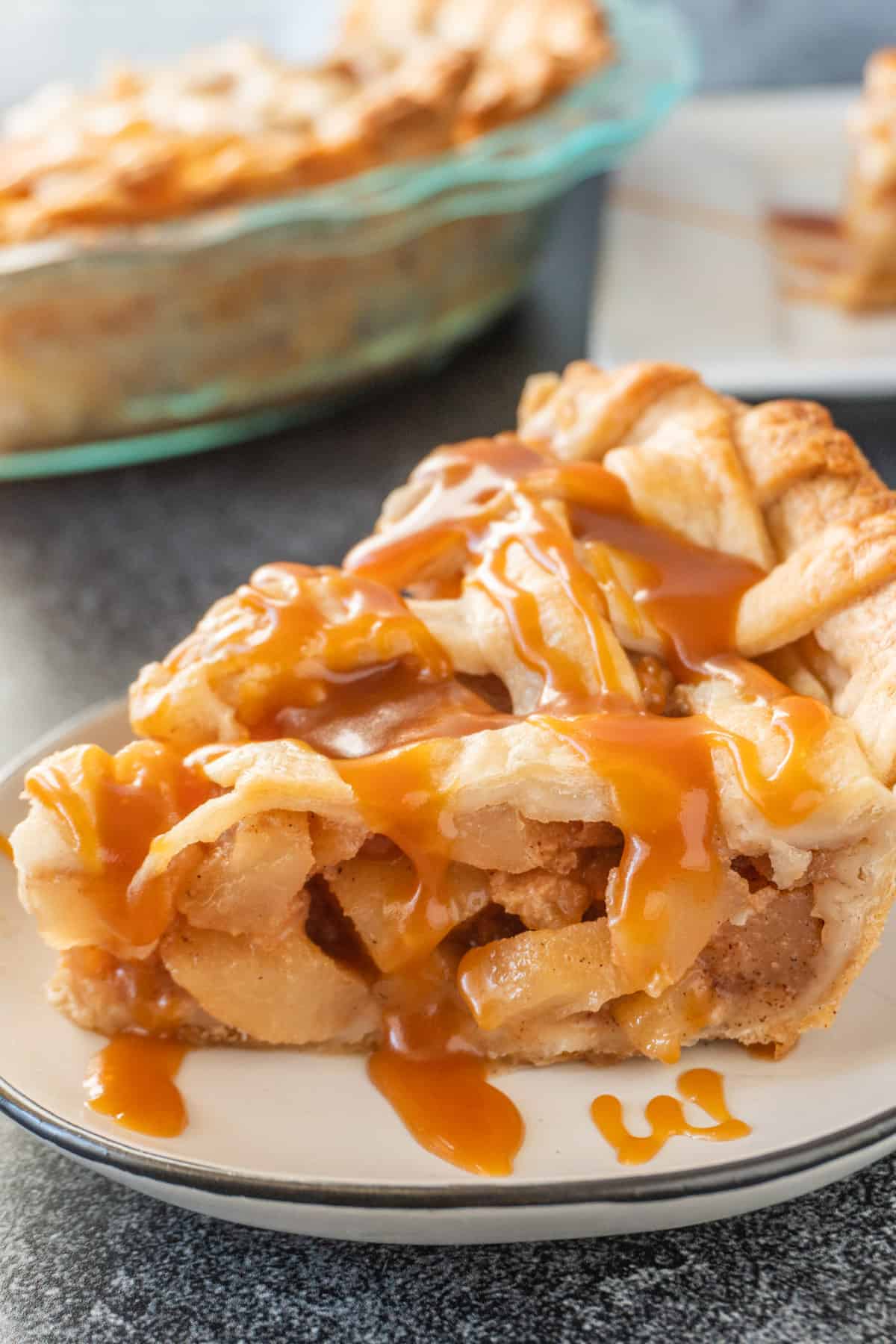 Caramel Pear Pie sliced, drizzled with caramel sauce, and on a white plate.