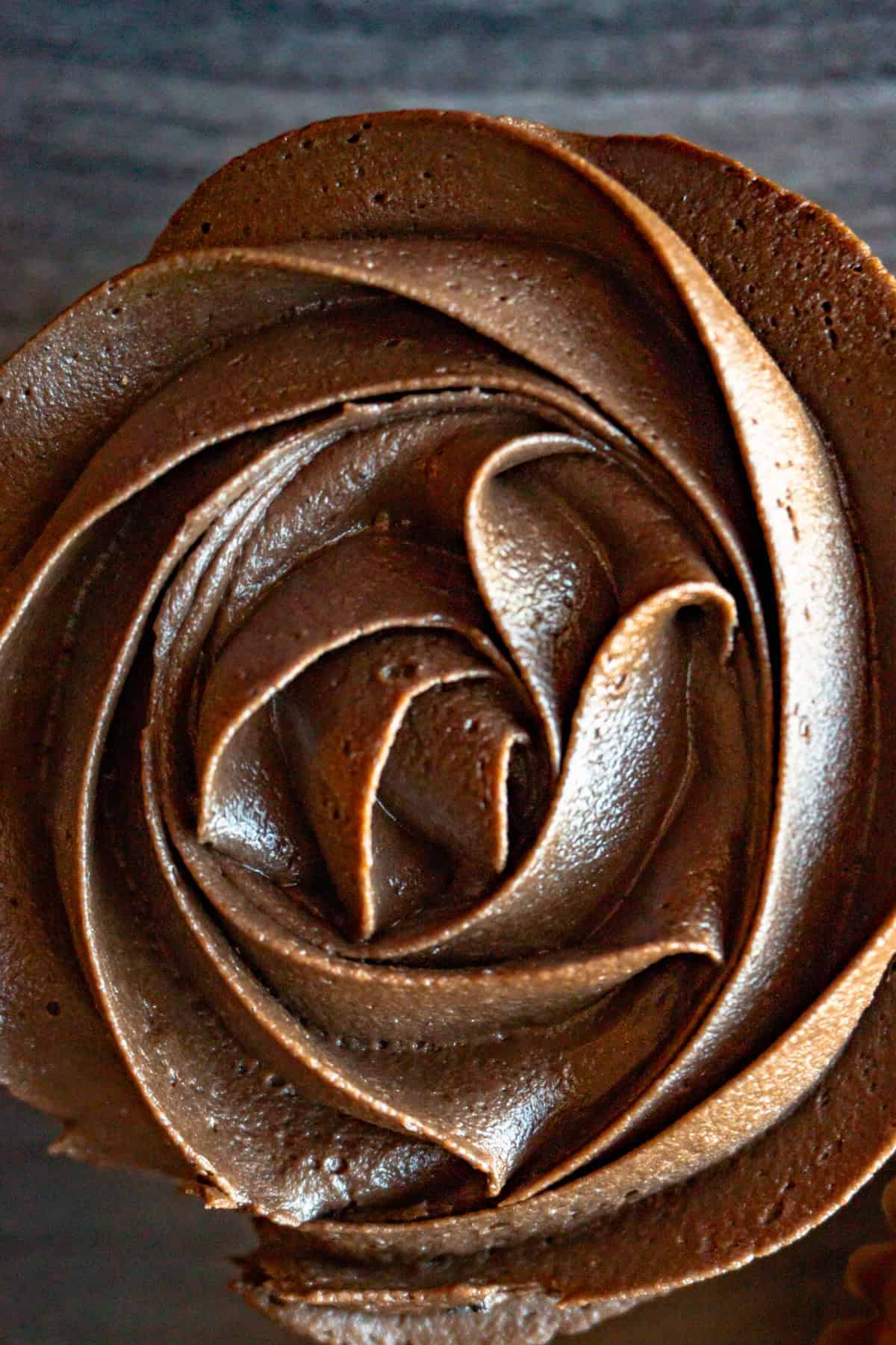 chocolate fudge frosting piped onto cupcake in a swirl pattern.