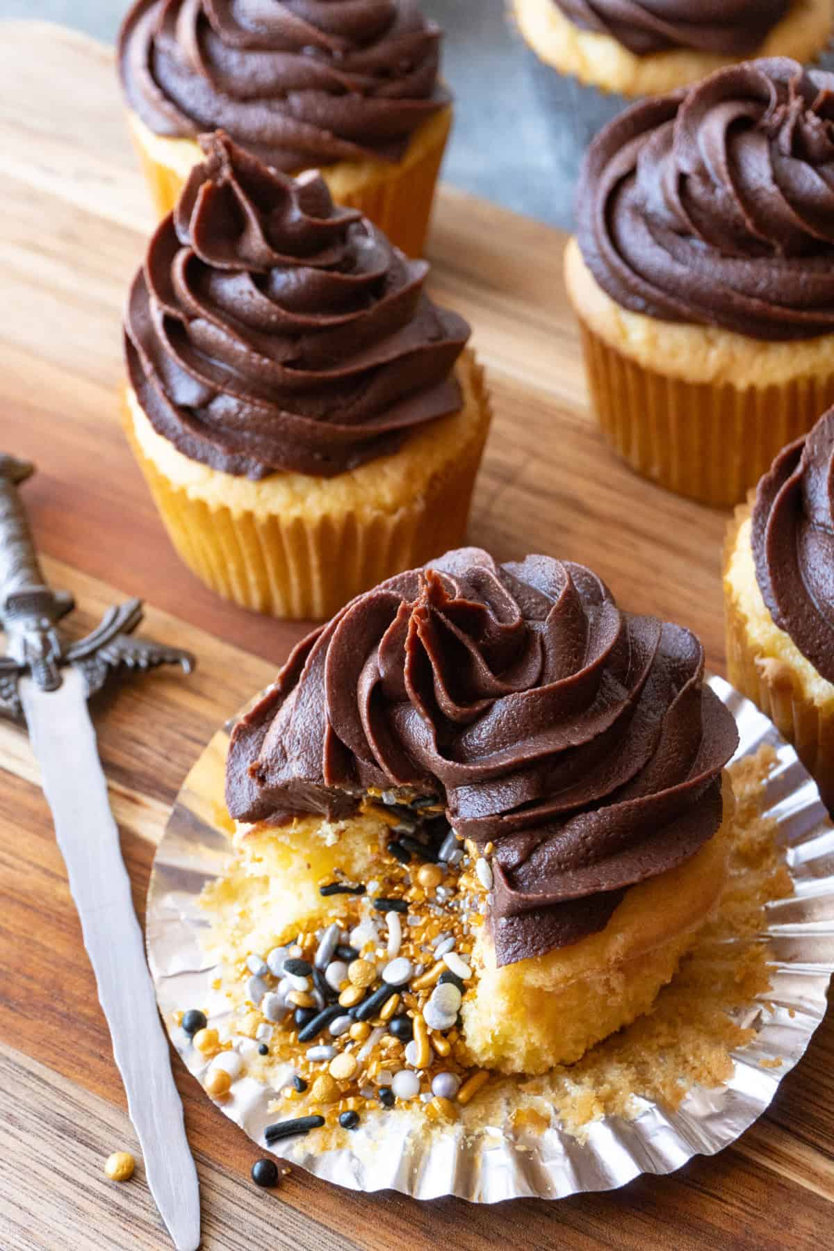 yellow cupcake with gold, silver, and black sprinkles