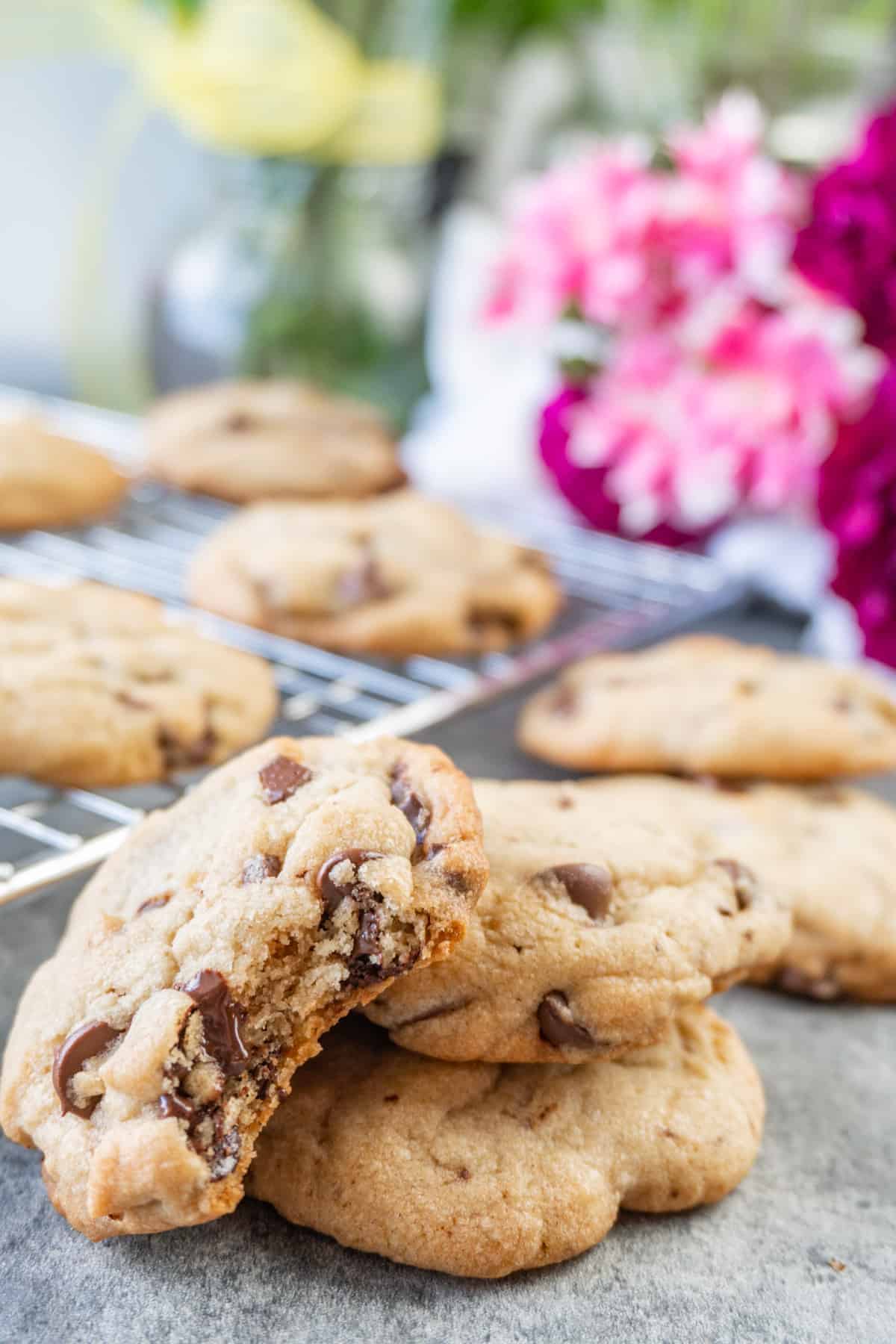 Betty Crocker Chocolate Chip Cookie Recipe cookie with bite taken out, flowers and cookies in background