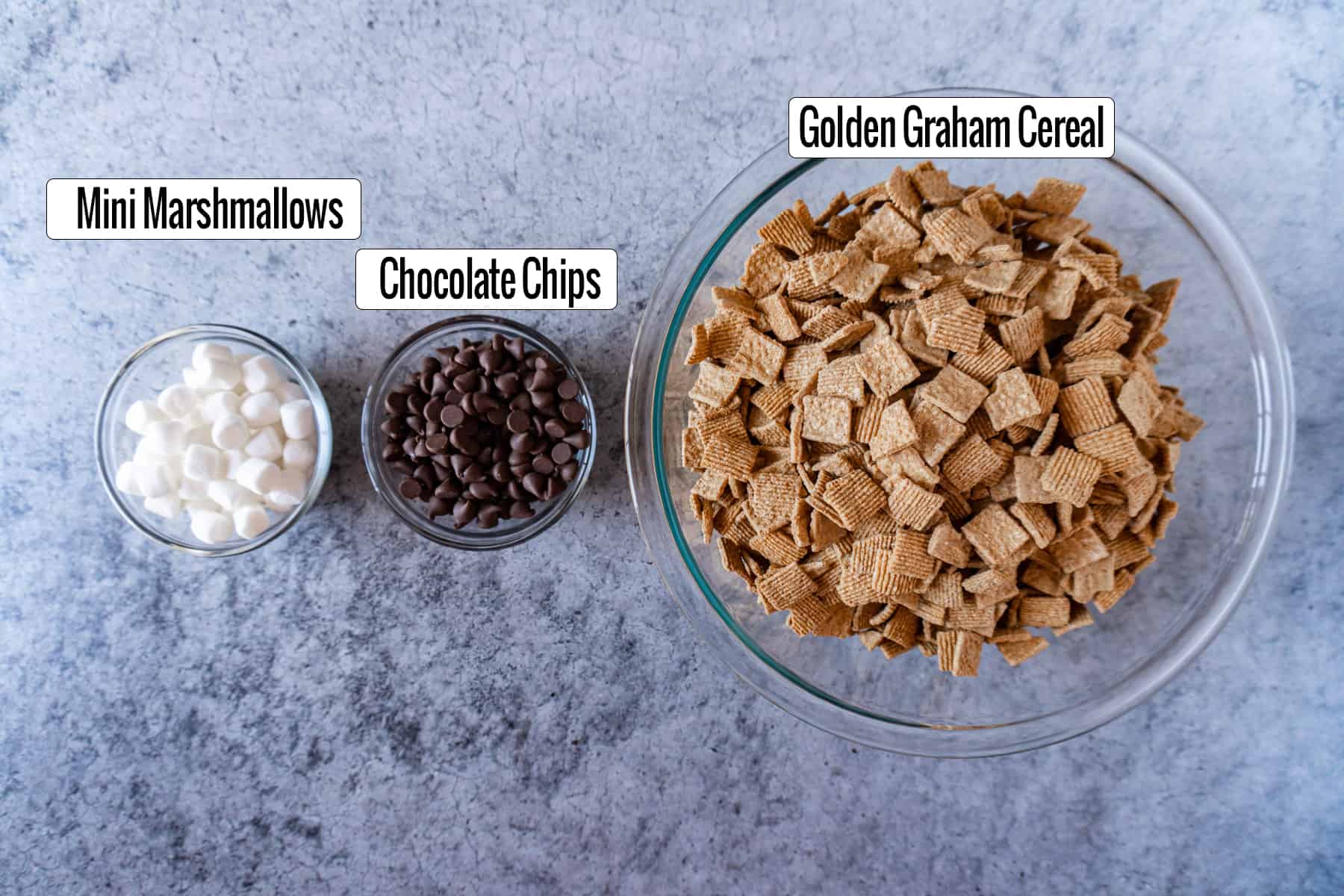 ingredients in bowls- golden graham cereal, chocolate chips, marshmallows