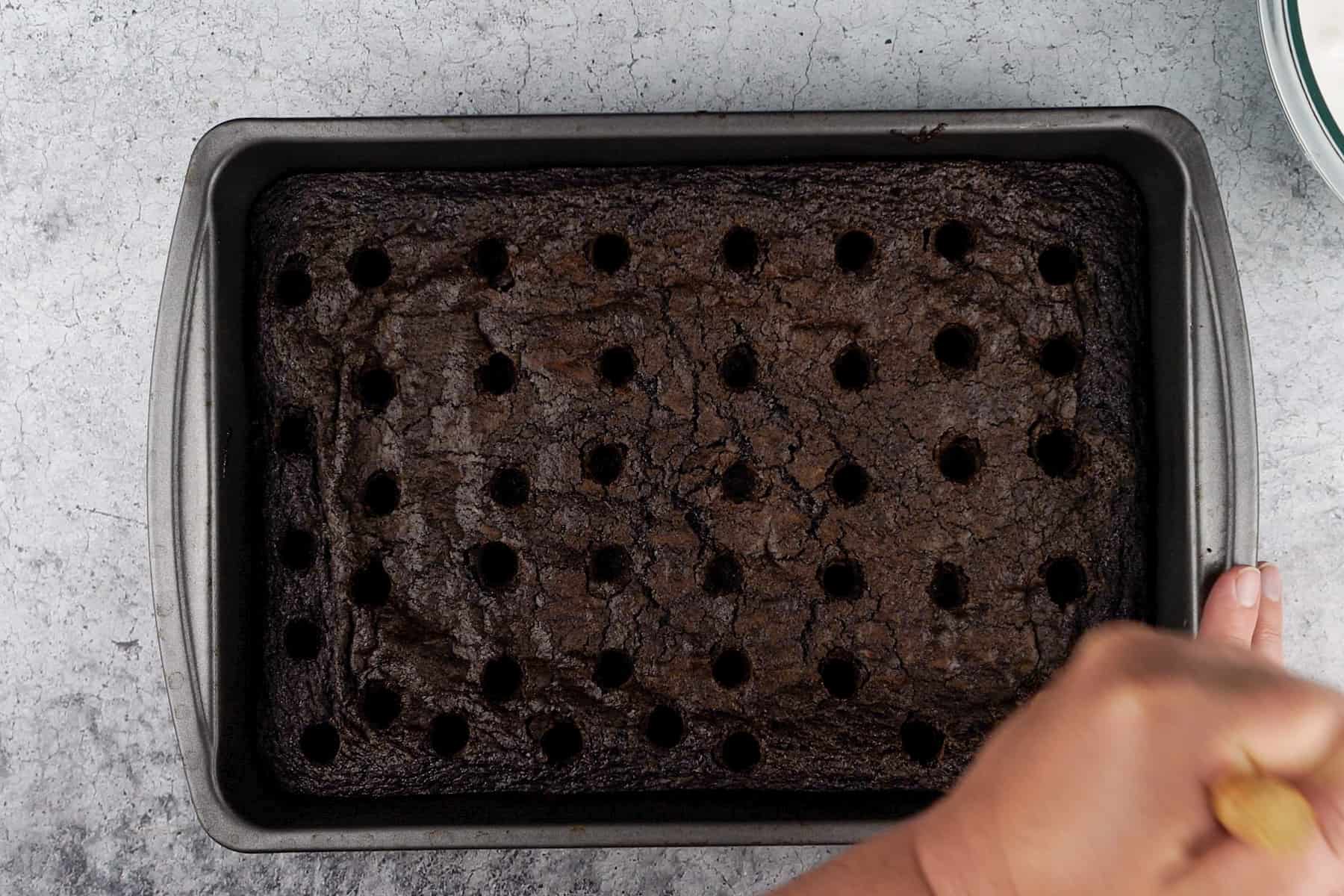 poking holes in baked brownies with wooden spoon handle