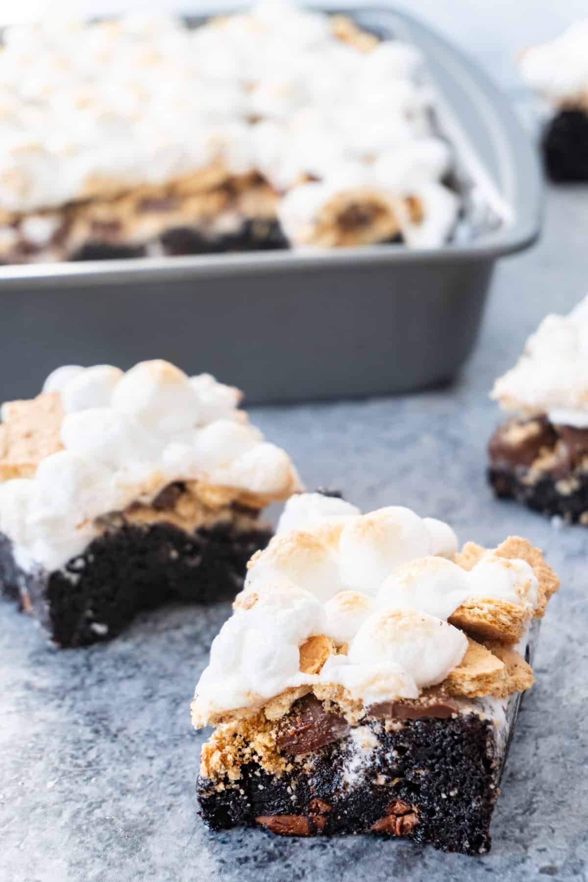 s'more brownies bars with pan of s'more brownies in background