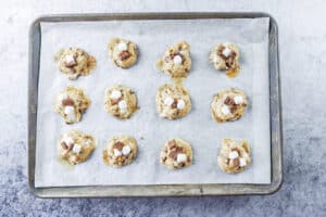 adding more marshmallows and chocolate to partially baked cookies