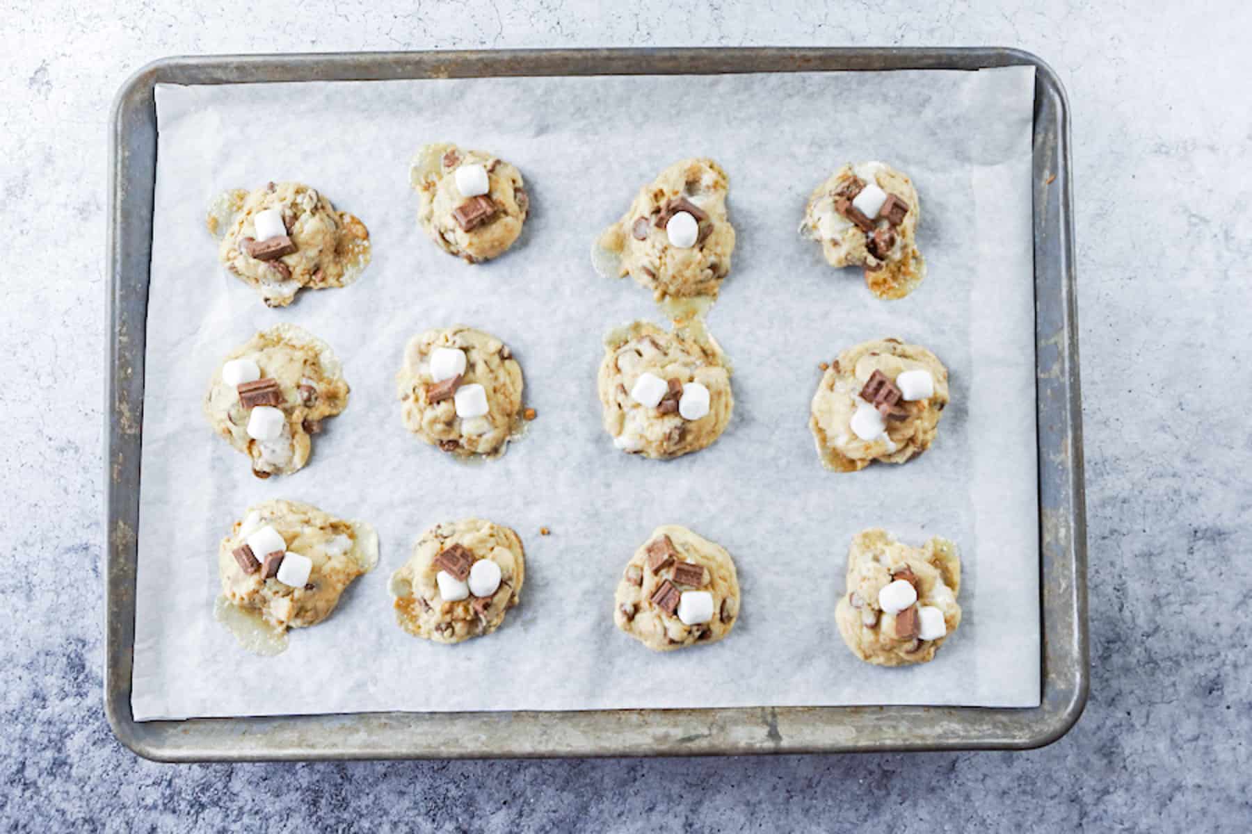 adding more marshmallows and chocolate to partially baked cookies