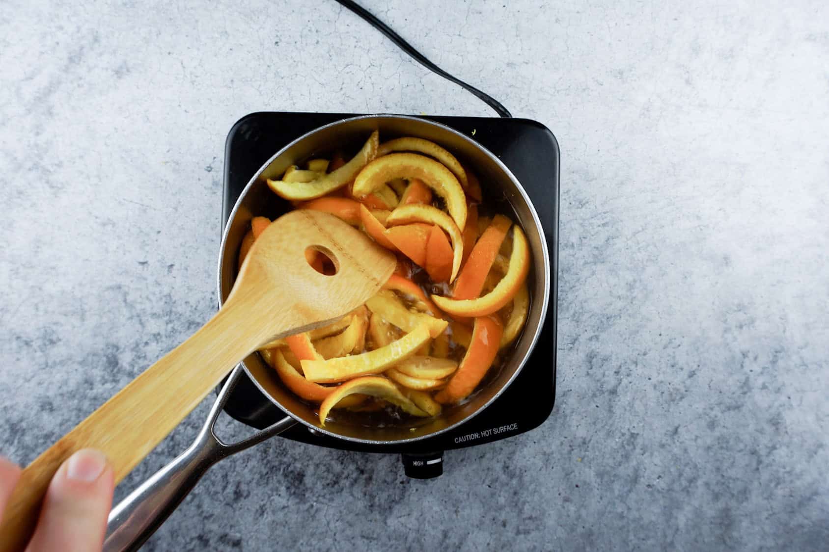 boiling orange peels in water in a sauce pan.