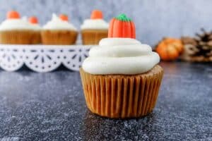 pumpkin cupcake with cream cheese frosting with cupcakes in background