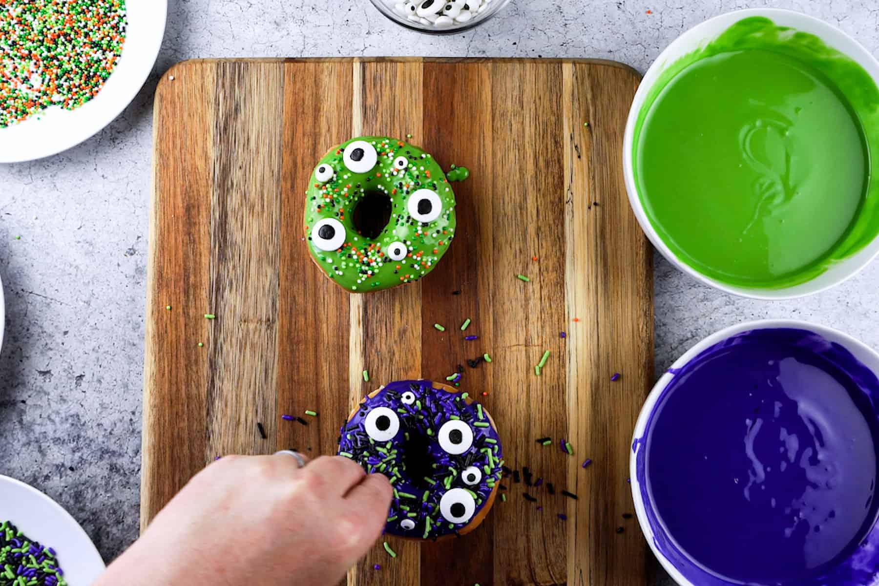 adding eyes and sprinkles to monster donuts.