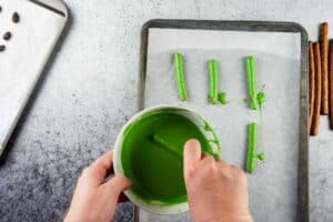coating a pretzel rod in green candy melts