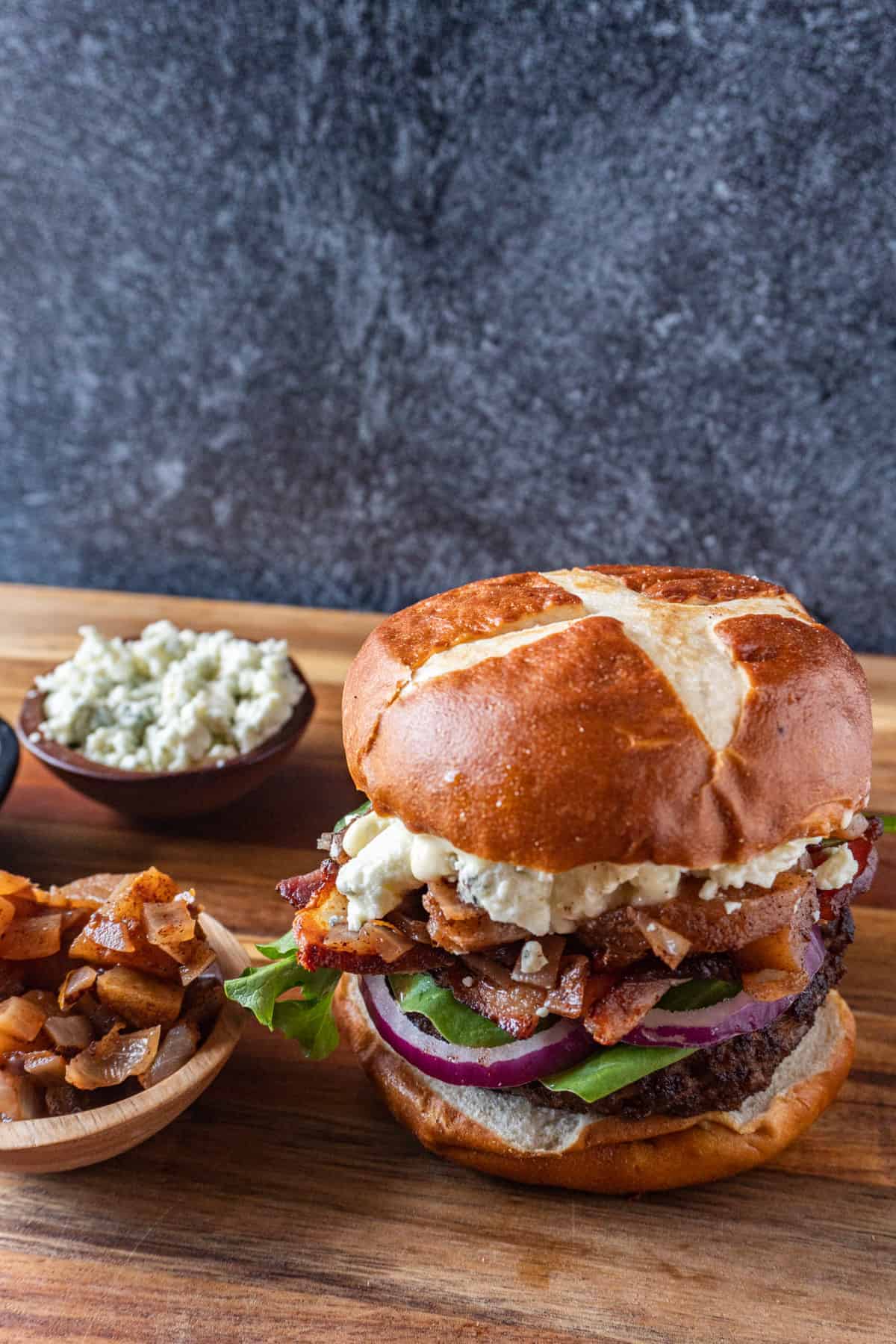 blue cheese burger on cutting board with extra condiments