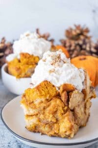 Close up of slice of pumpkin bread pudding with whipped cream on top