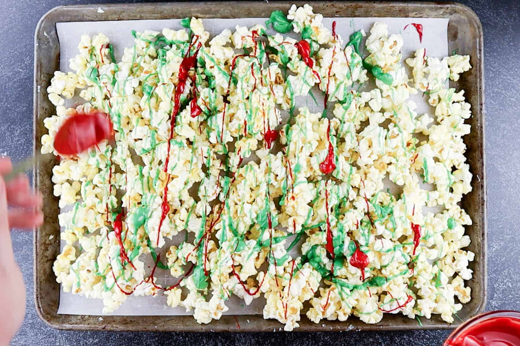 Drizzling red and green candy melts over popcorn.