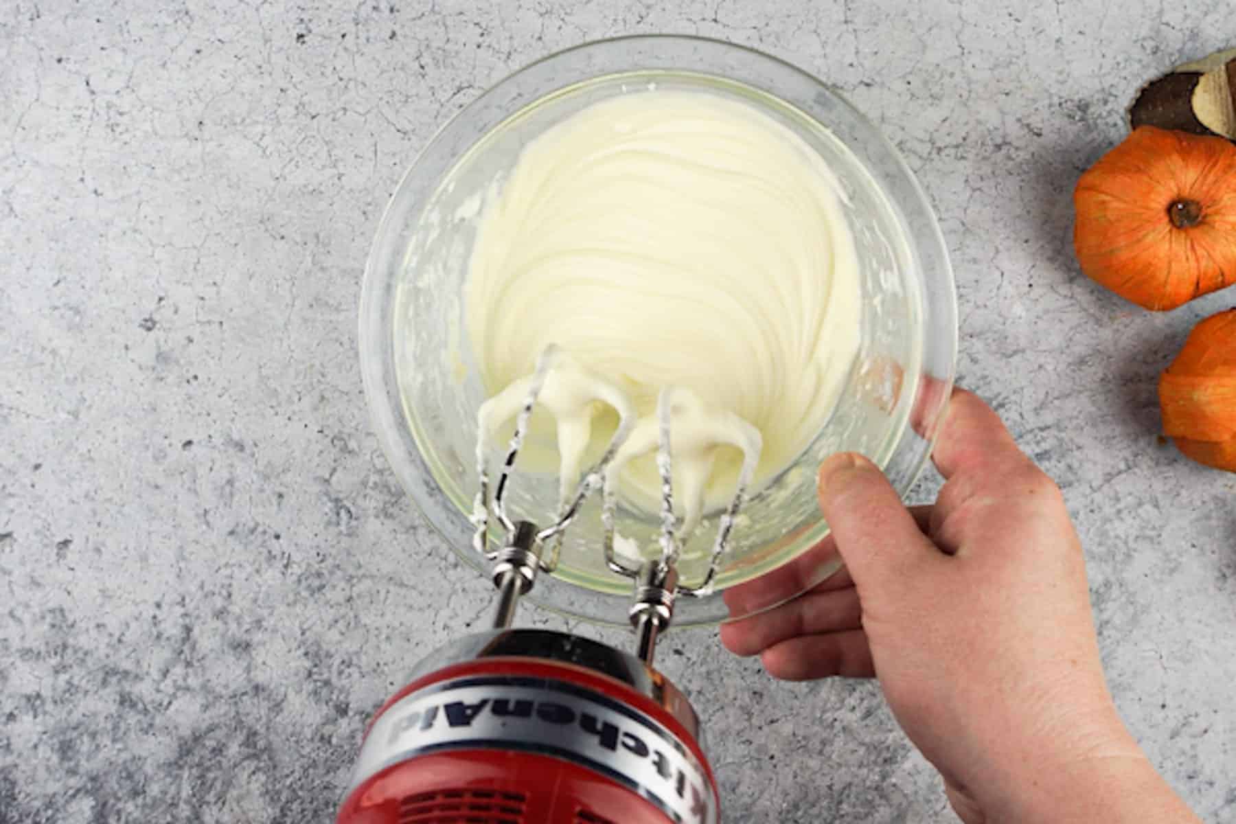 cream cheese mixture for pumpkin bread mixed in clear glass bowl.