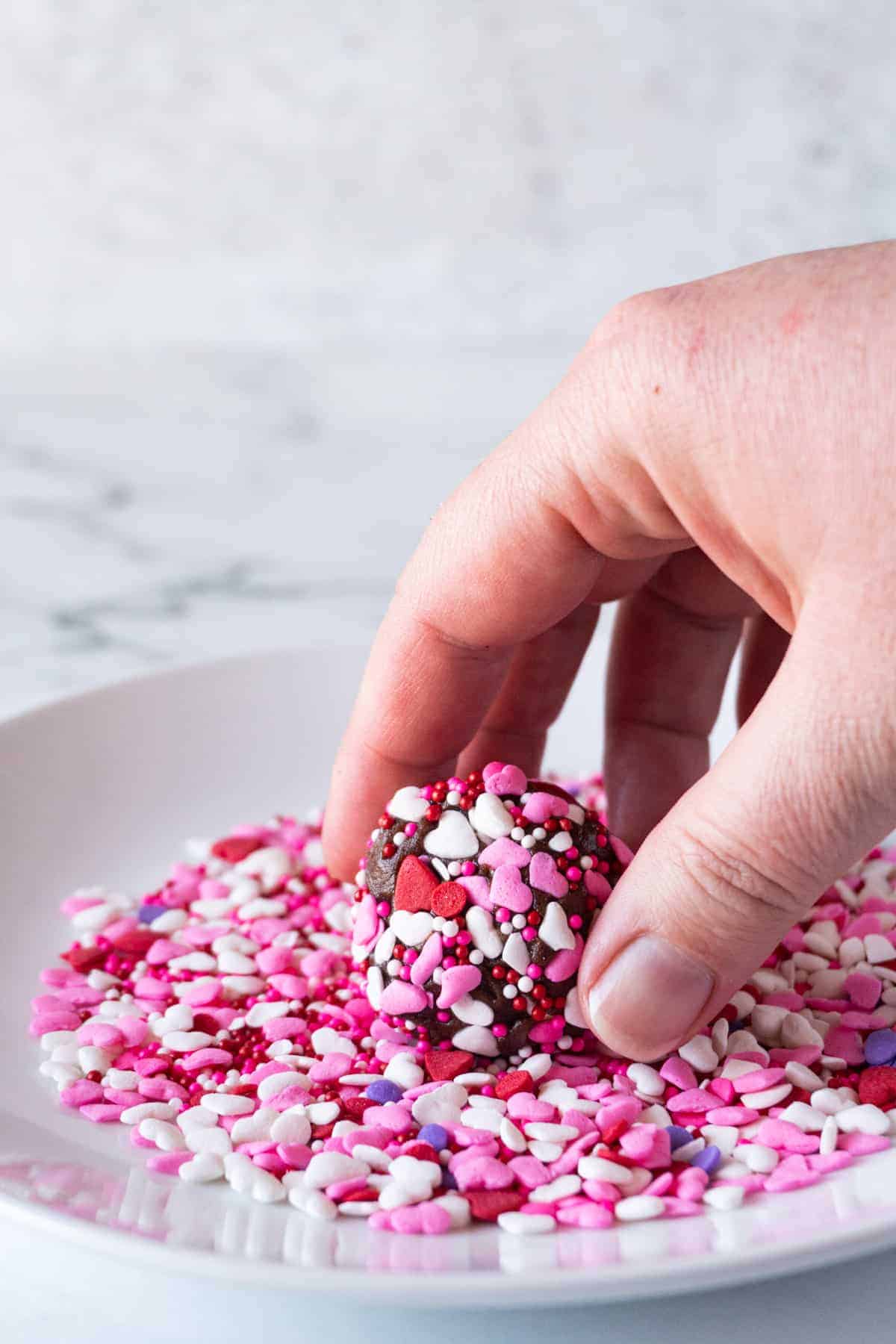 rolling the cookie dough ball in sprinkles