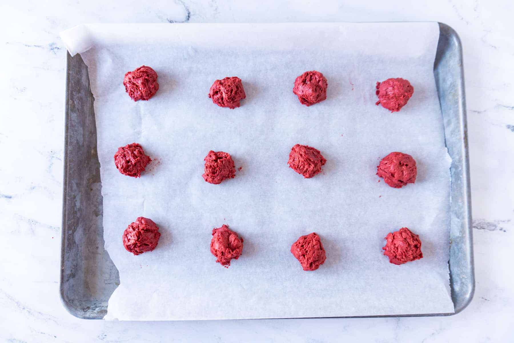 red velvet cake cookie dough scooped onto baking sheet.