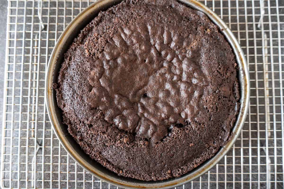 chocolate cake baked in a metal cake pan with a sunken center.