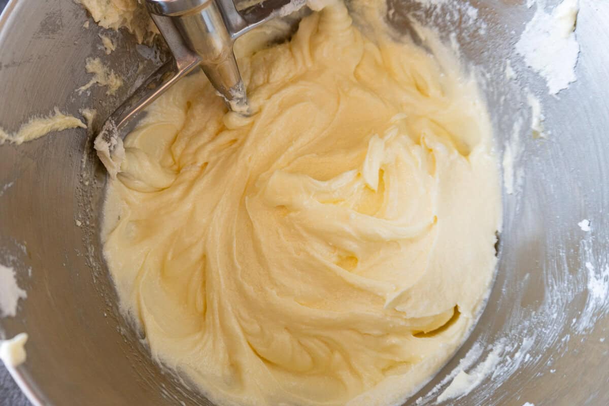 oil and eggs mixed into butter and sugar to create a batter, in a metal bowl.
