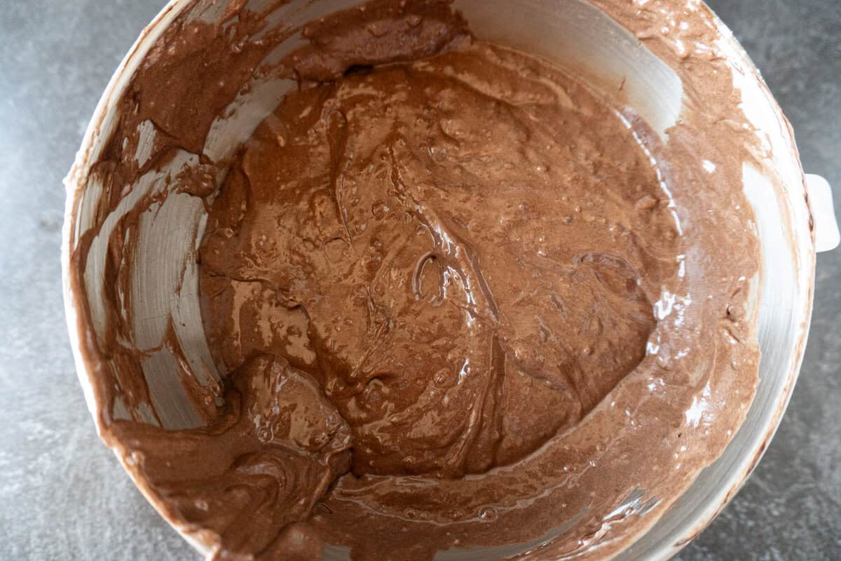 cake batter folded together with the chocolate mixture and flour mixture in a metal bowl.