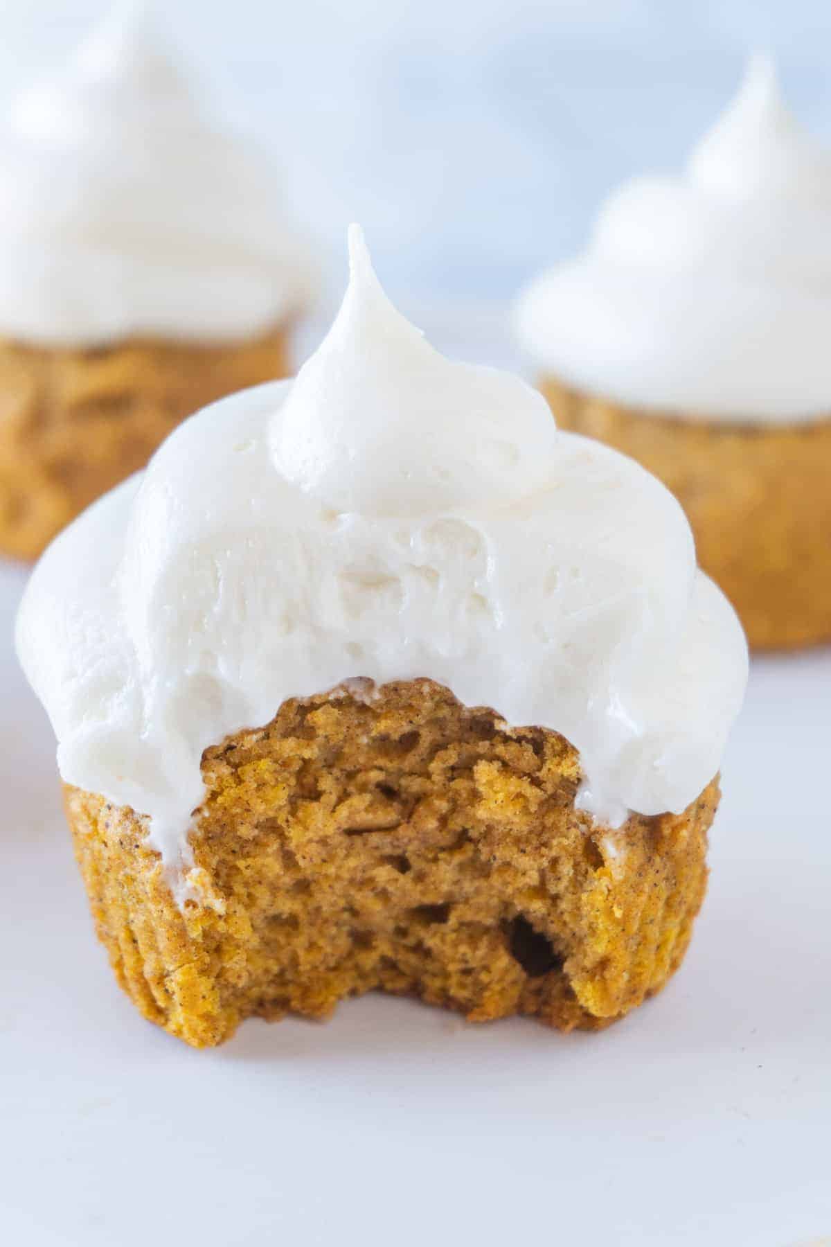 This Cream Cheese Frosting is so good you will want to frost everything with it! Sweet, delicious, and perfect for your next cake, cupcake, or cookie! #easy #recipe #forcupcakes #forcake #forcinnamonrolls #for cookies #whipped #pipeable #redvelvet #homeade #fluffy #forpiping Cream Cheese Frosting on cupcake with bite taken out