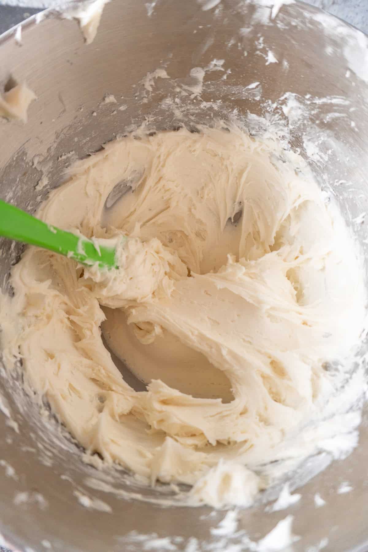 cream cheese butter mixture mixed with vanilla and salt in metal mixing bowl.