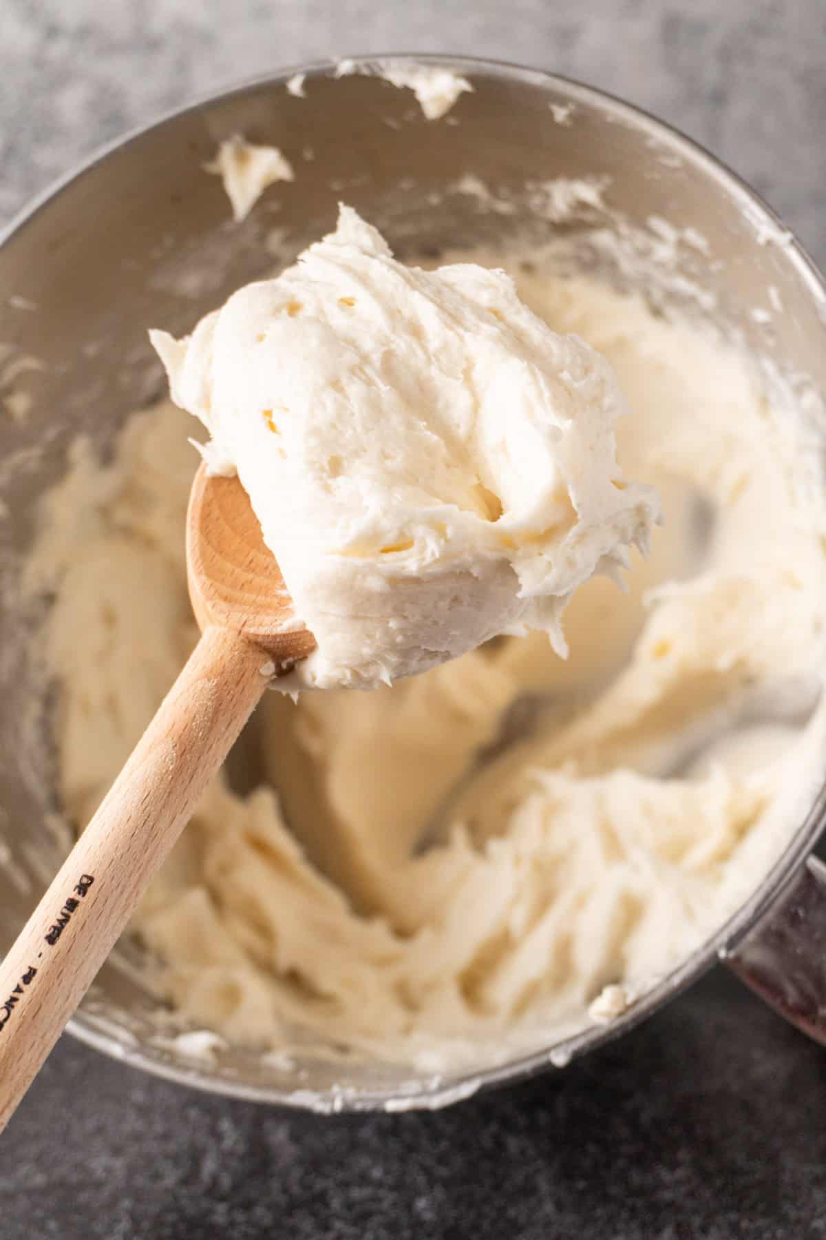 cream cheese frosting scooped onto wooden spoon.