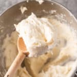 whipped cream cheese frosting recipe in wooden spoon featured image.