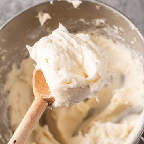 whipped cream cheese frosting recipe in wooden spoon featured image.