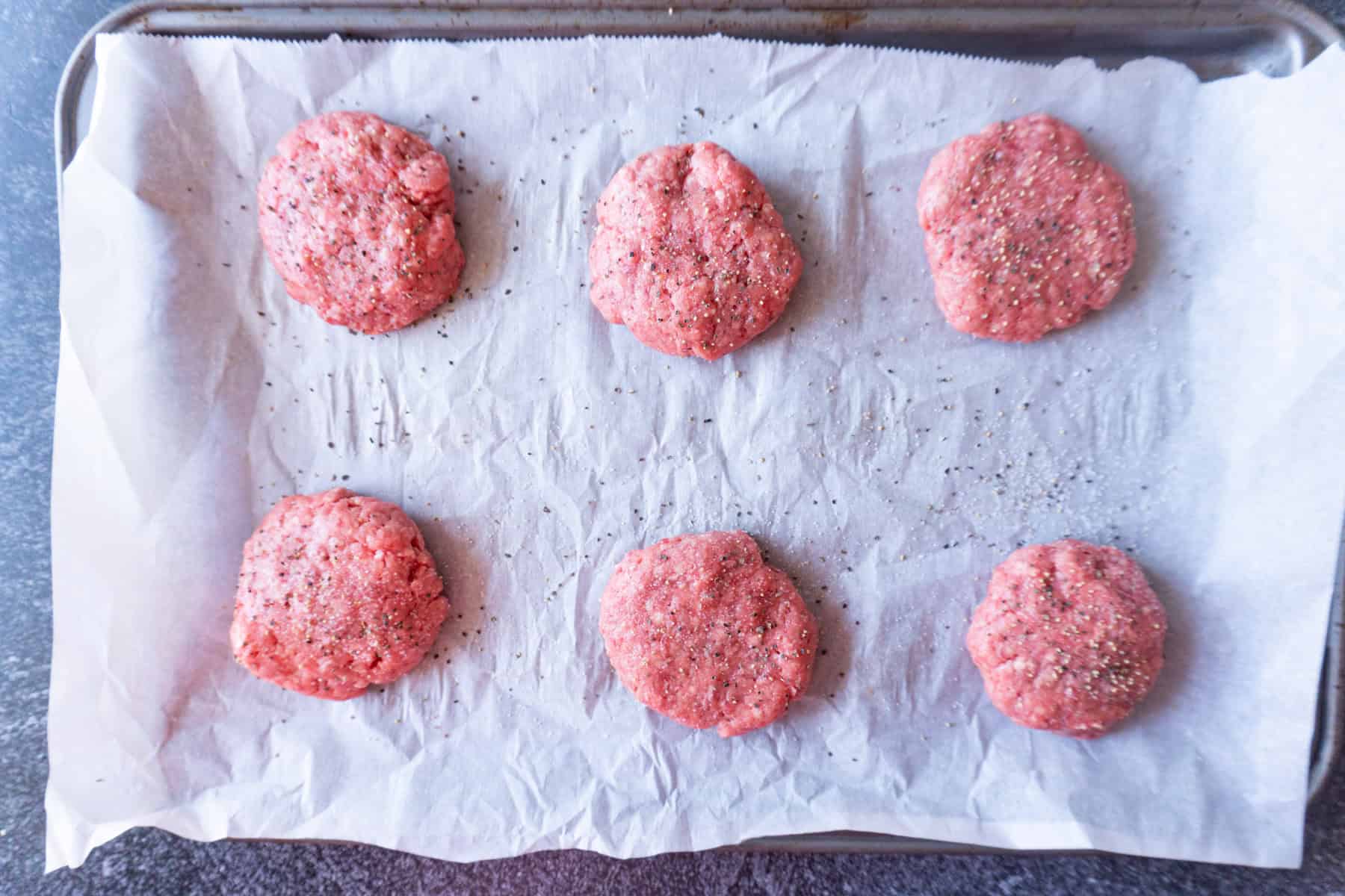 each ground beef ball slightly flattened and sprinkled with salt and pepper.
