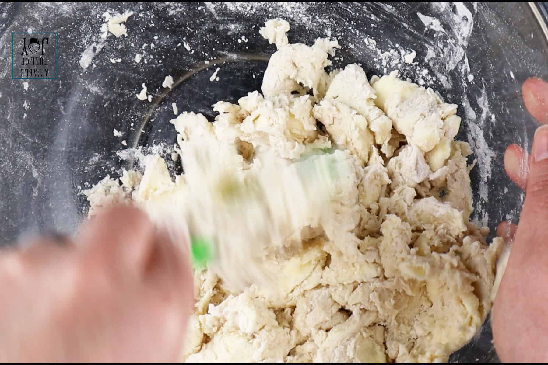 Mixing the the pie dough in a clear glass bowl.