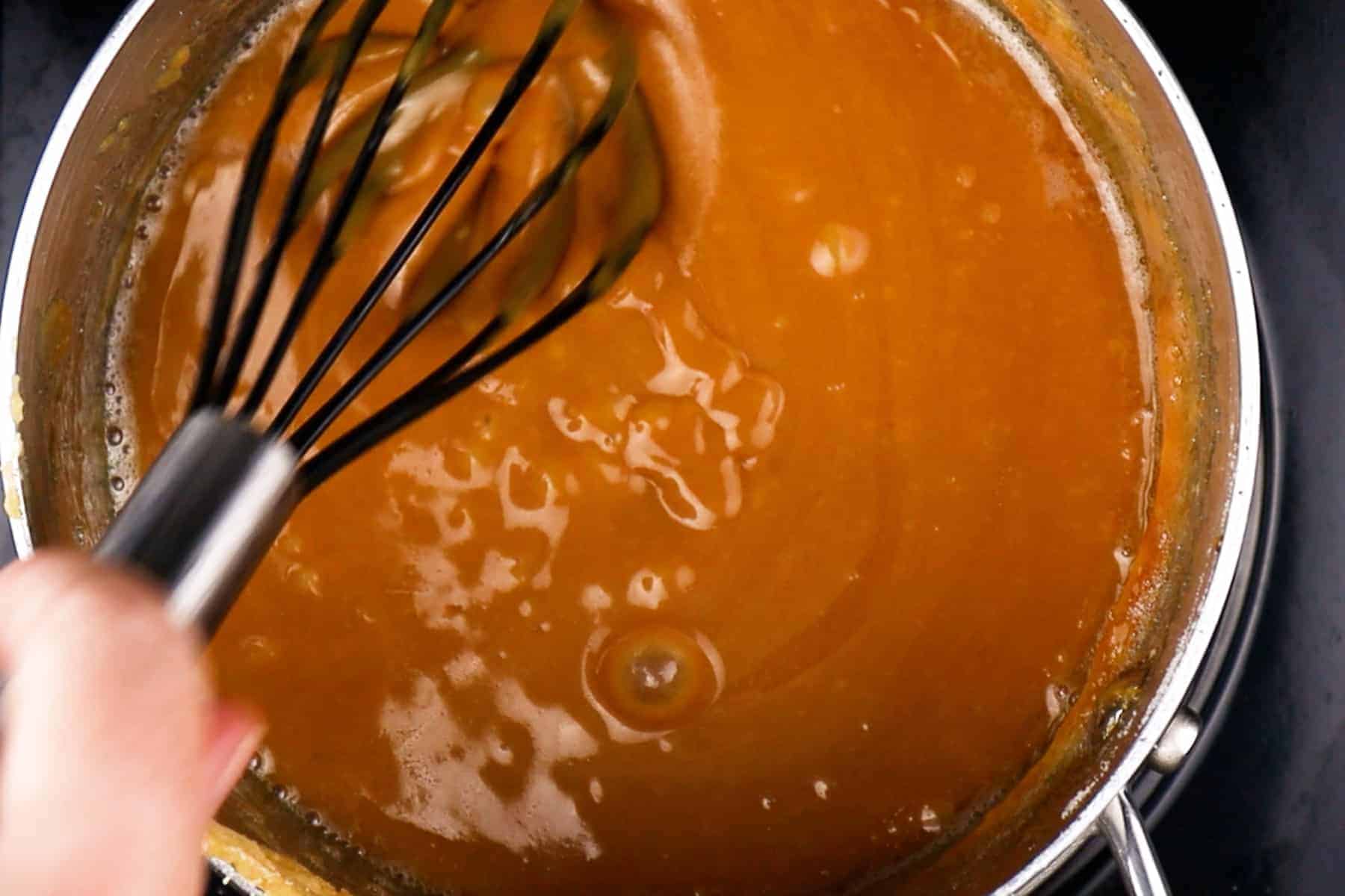 Caramel sauce in a pan, stirring with a whisk.