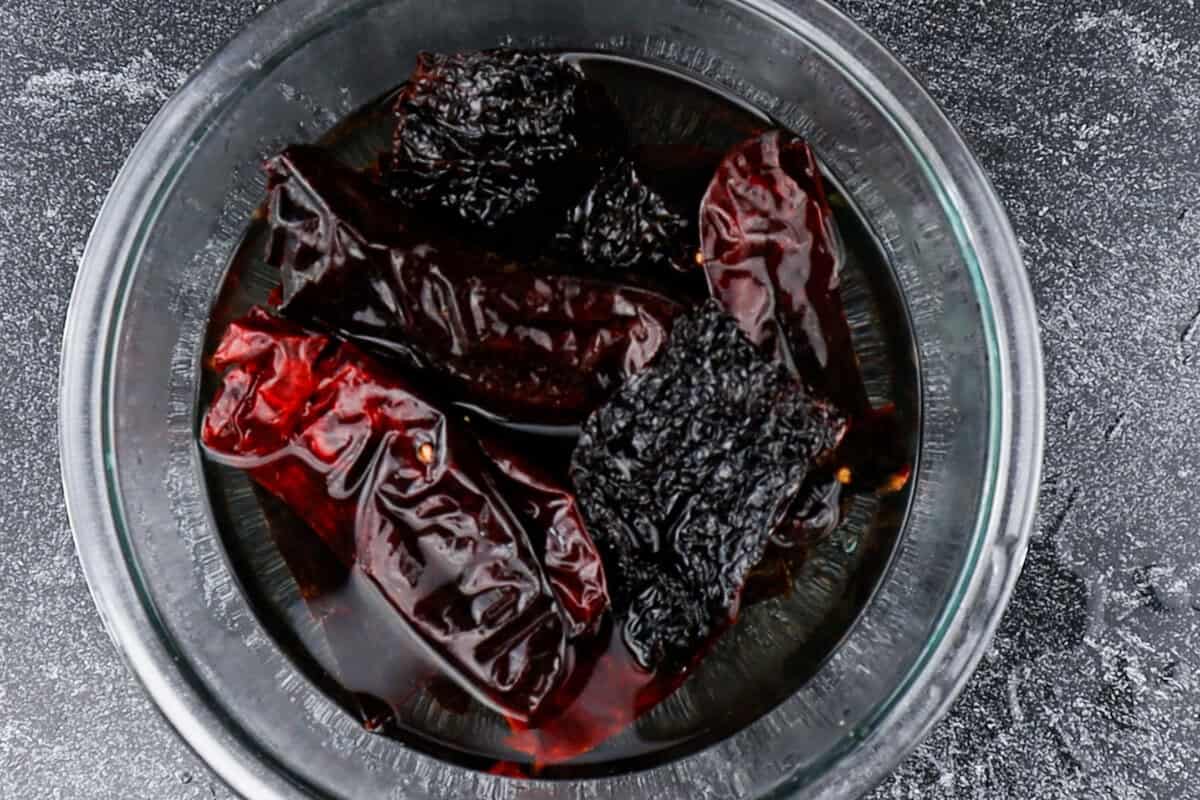 soaking roasted dried chiles in water in clear glass bowl.