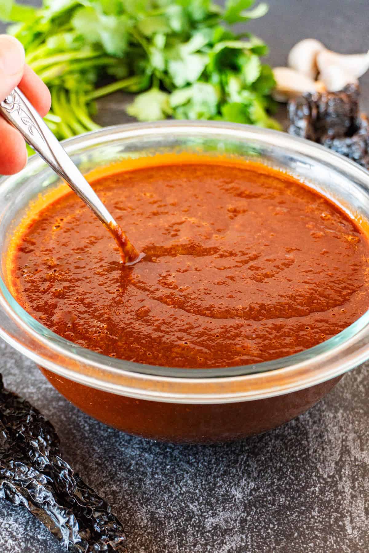 stirring red enchilada sauce with metal spoon.