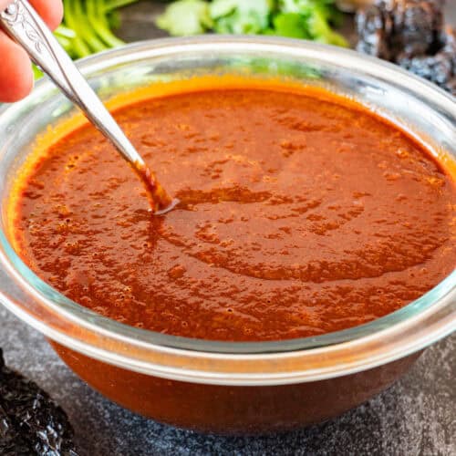 stirring red enchilada sauce with a metal spoon- featured image