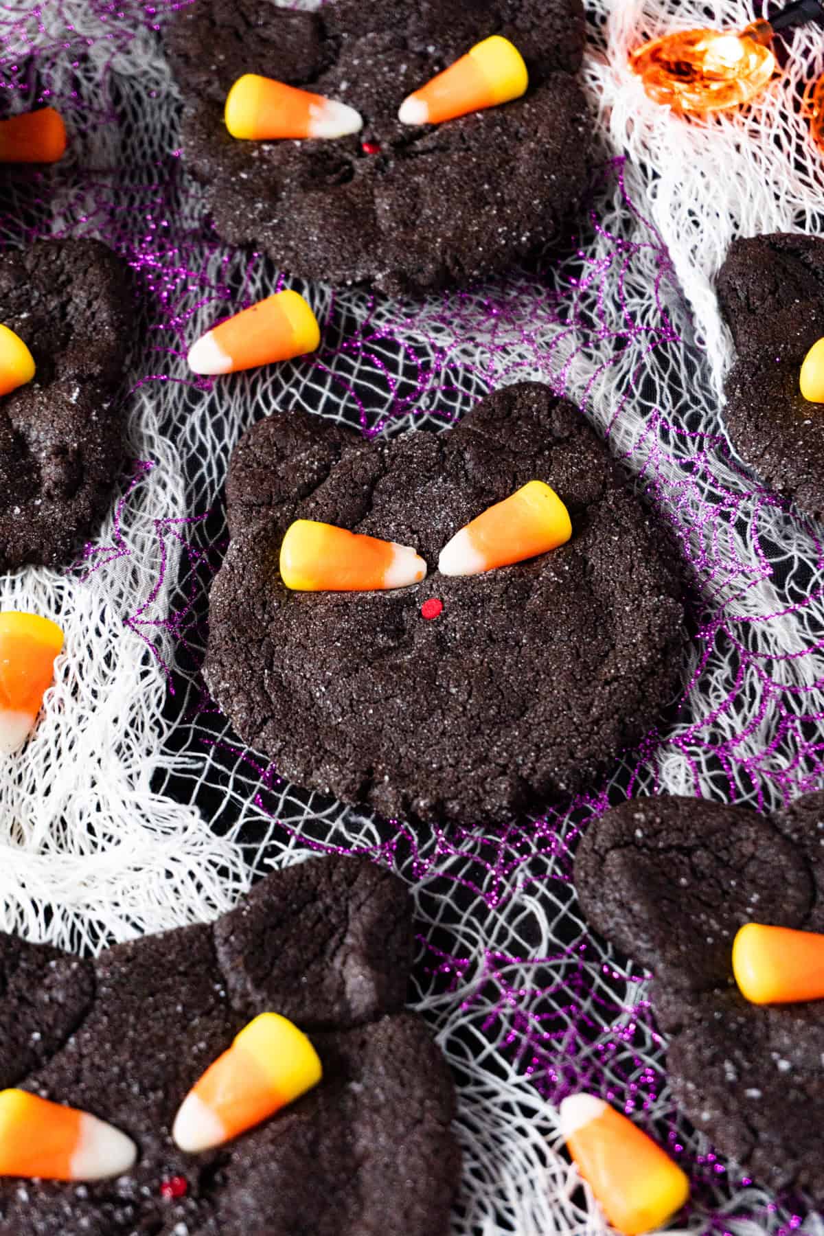 black cat cookies on purple and white cheesecloth background.