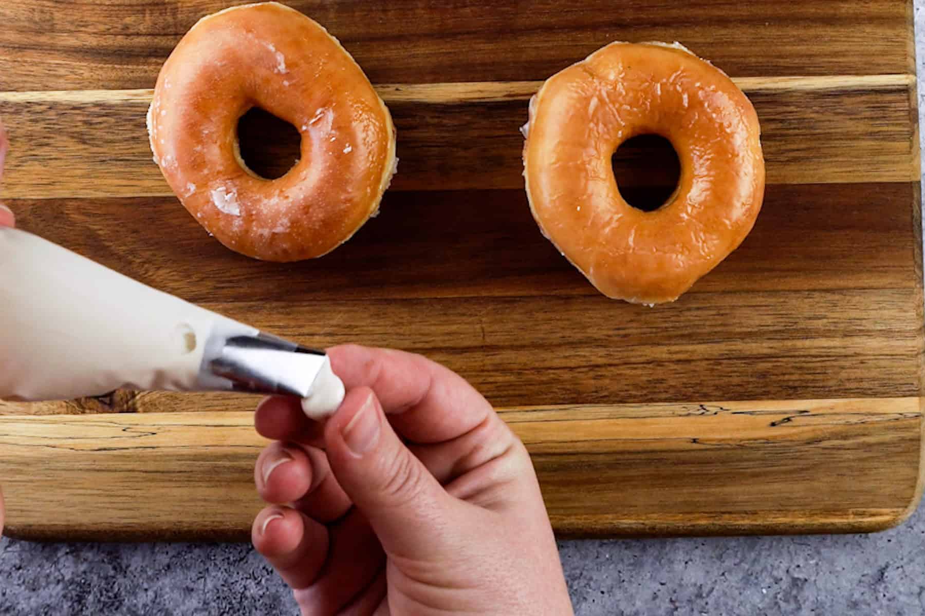adding candy melt to the back of a candy eye before placing it on a glazed donut.