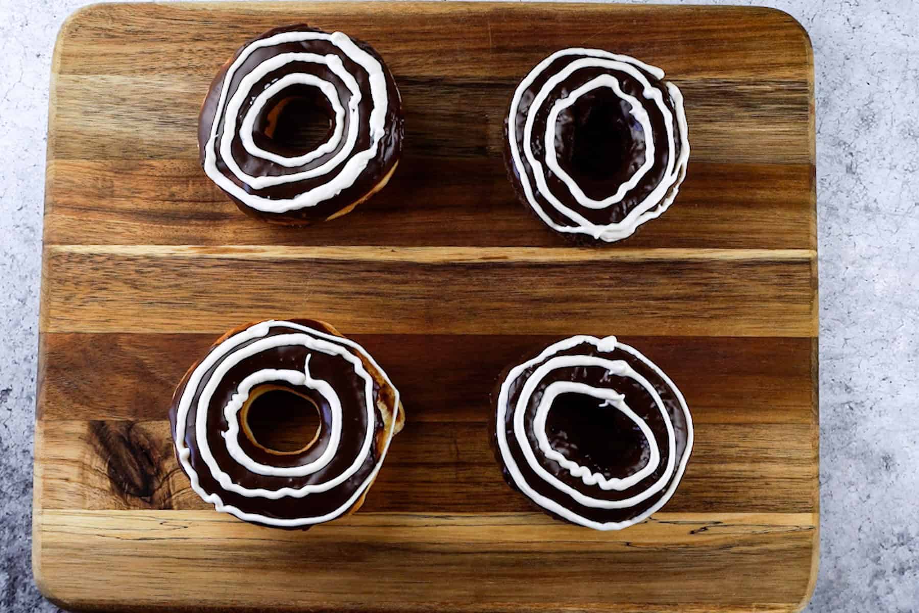 concentric white circles piped onto chocolate-dipped donuts.