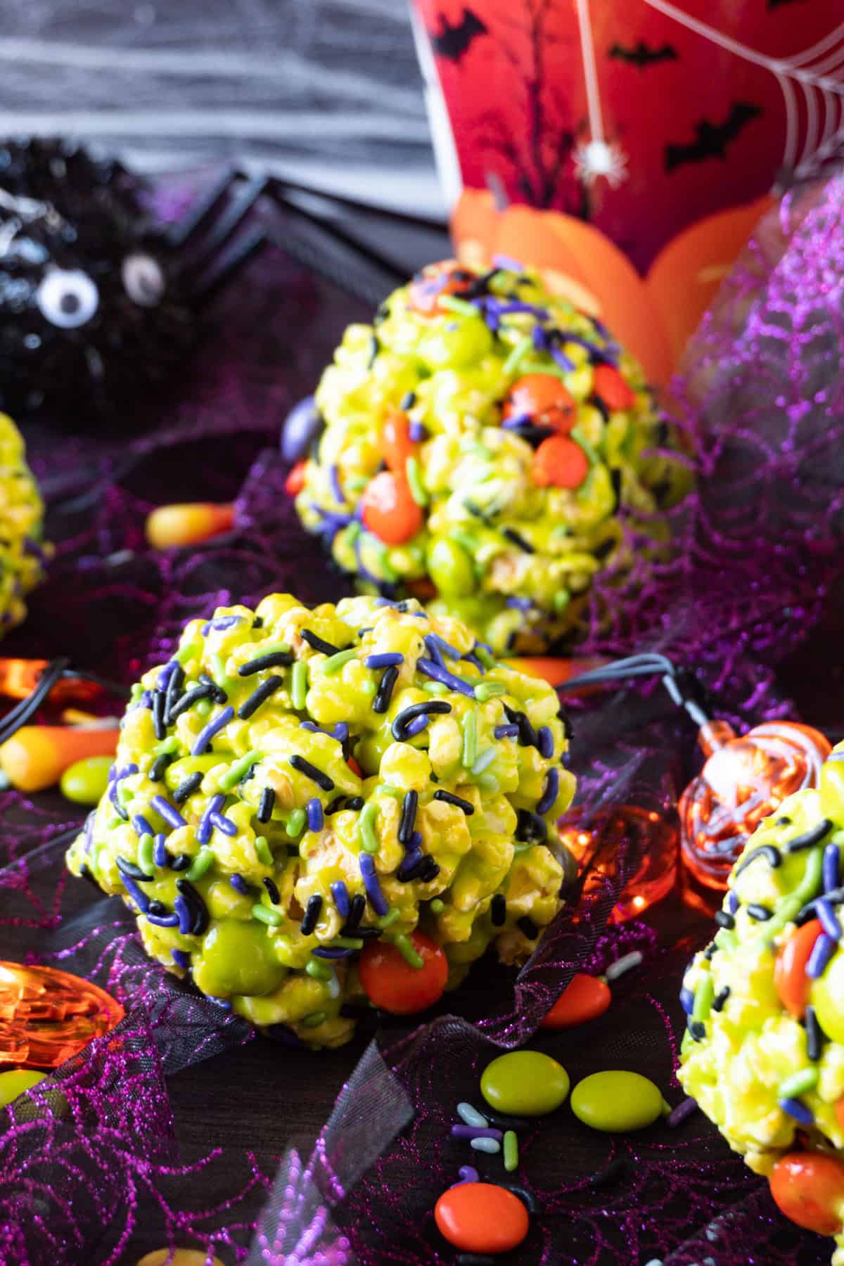 green halloween popcorn balls with sprinkles and M&M's mixed in.
