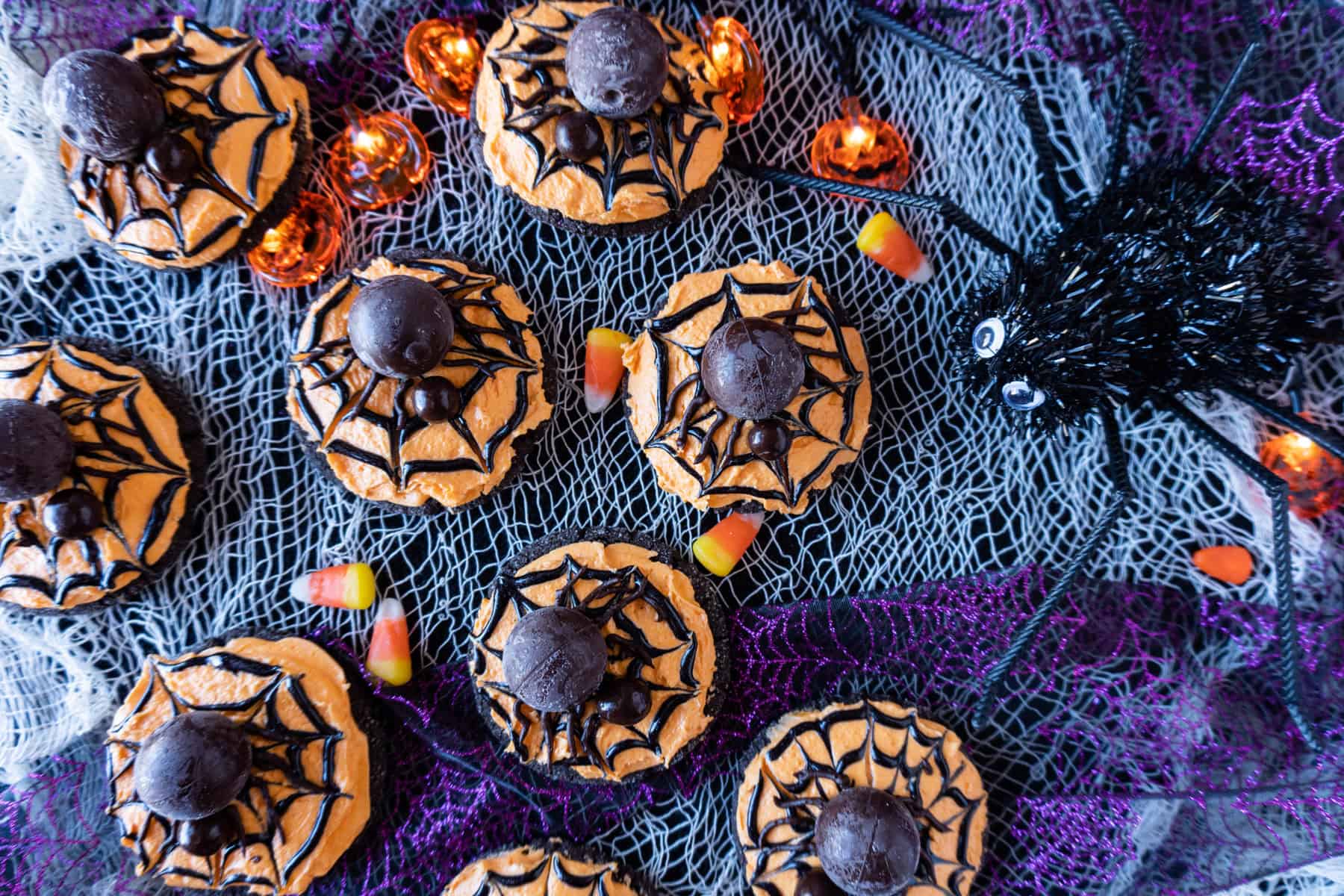 spider cookies on a blue and purple background with a large fake spider nearby.