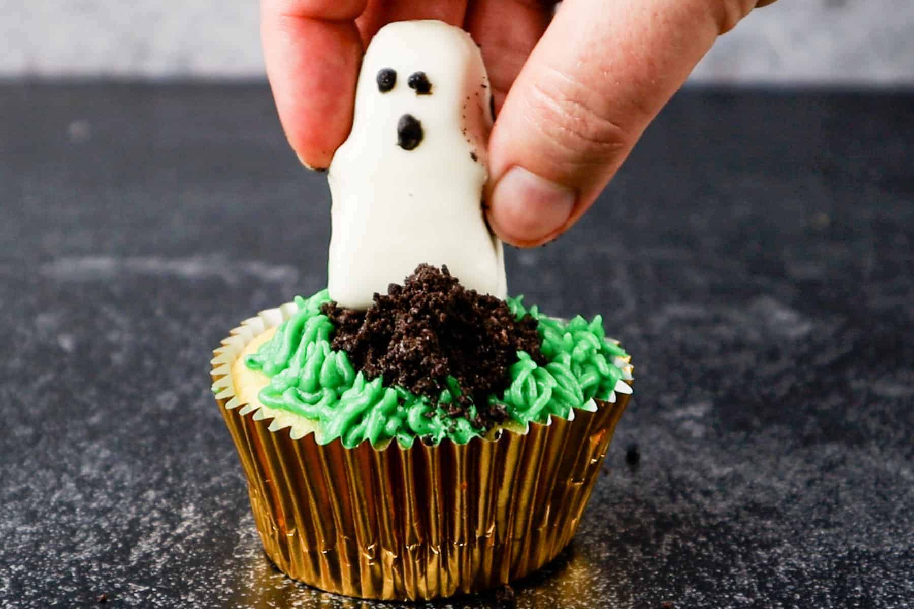 Halloween Graveyard Cupcake with Reese's White Chocolate Ghost added to Crushed Oreo Mound on top of cupcake.