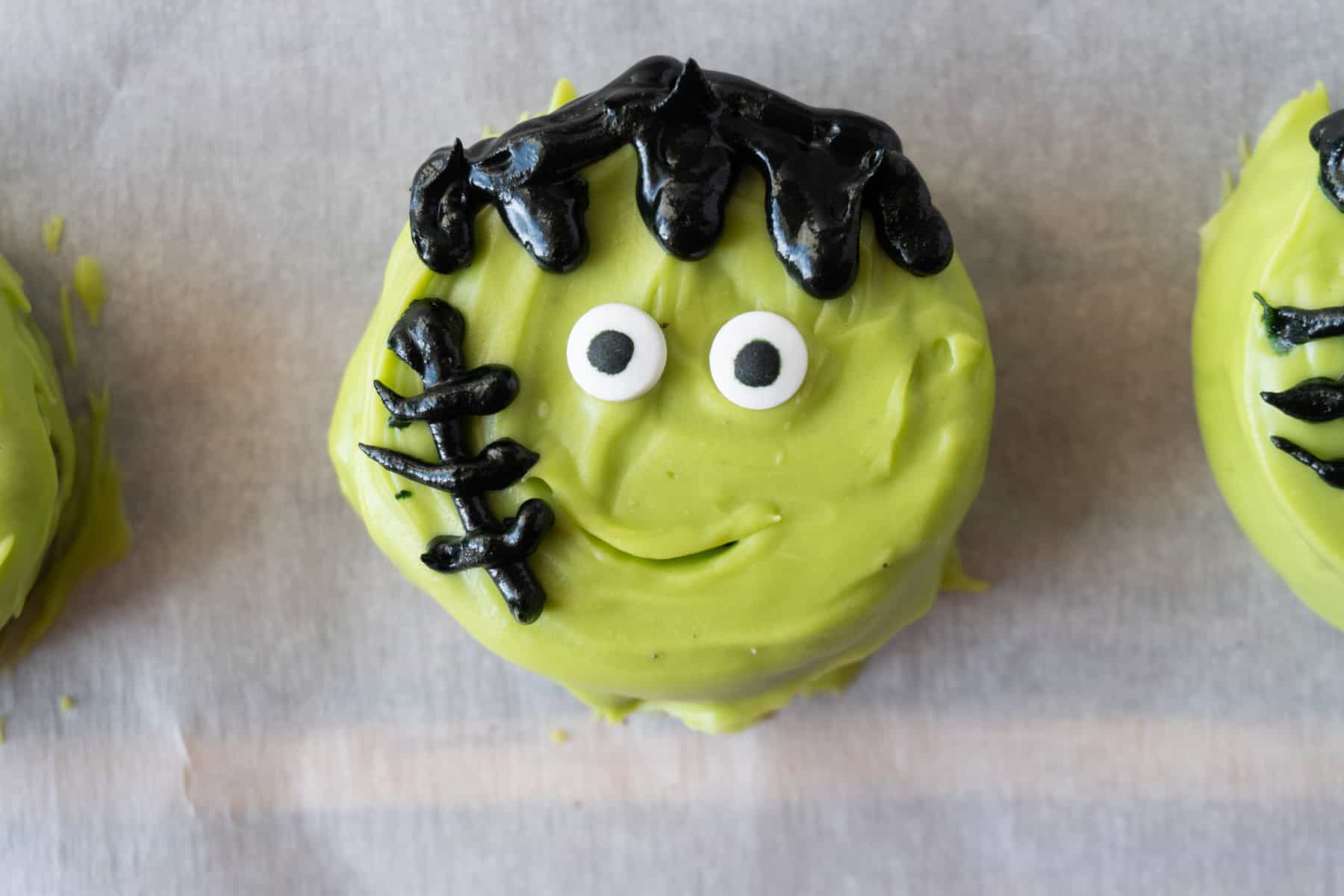 Oreo covered in green candy melts decorated to look like Frankenstein's Monster.