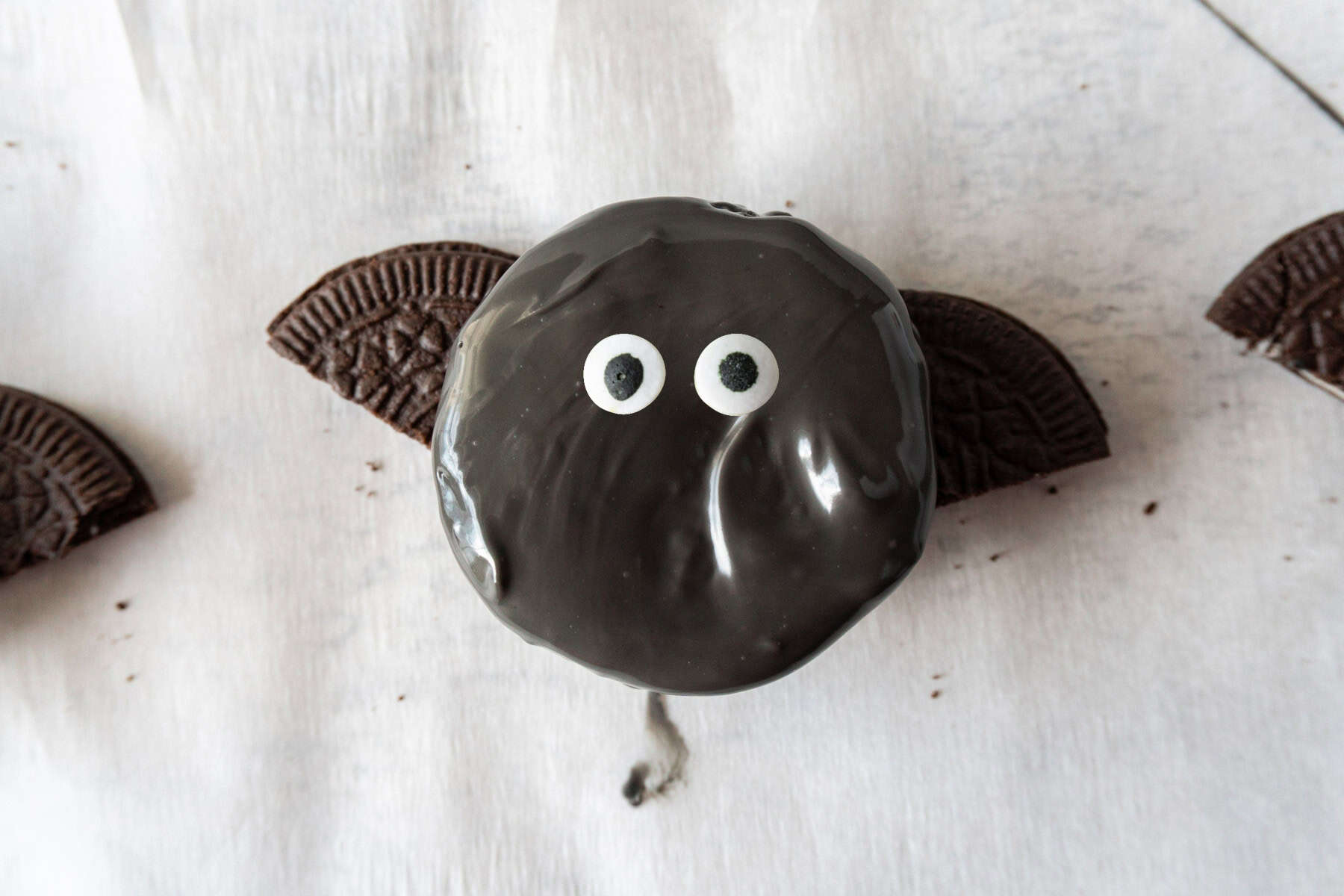 Oreo covered in black candy melts, sitting on two thin Oreo halves, with candy eyes pressed on.