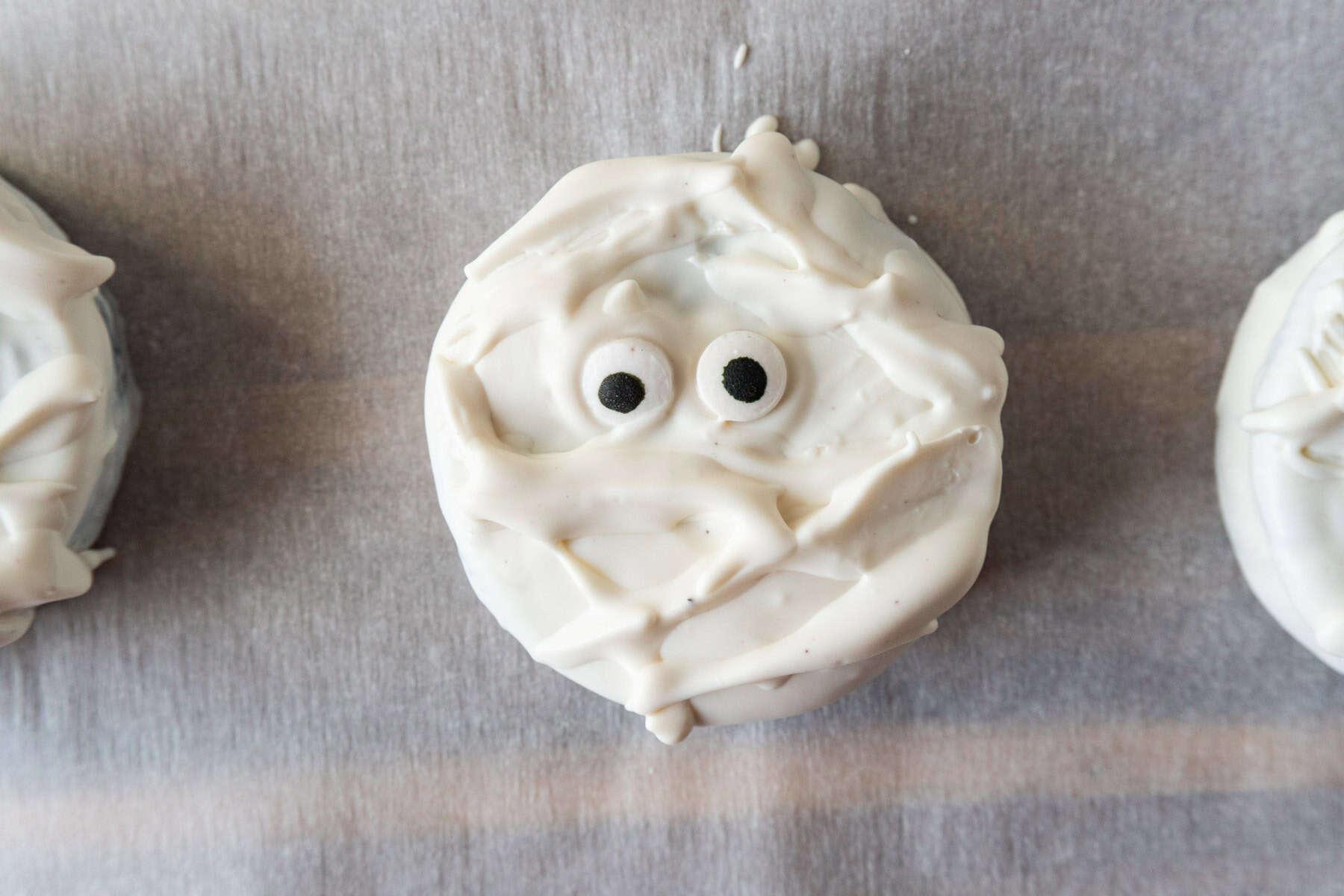 Oreo covered in white candy melts with candy eyes pressed on and extra white candy melts drizzled on to look like mummy bandages.