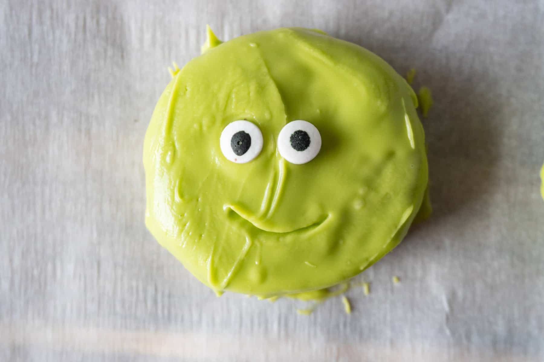 Oreos covered in green candy melts with candy eyes pressed on and a mouth indent drawn on with a toothpick.