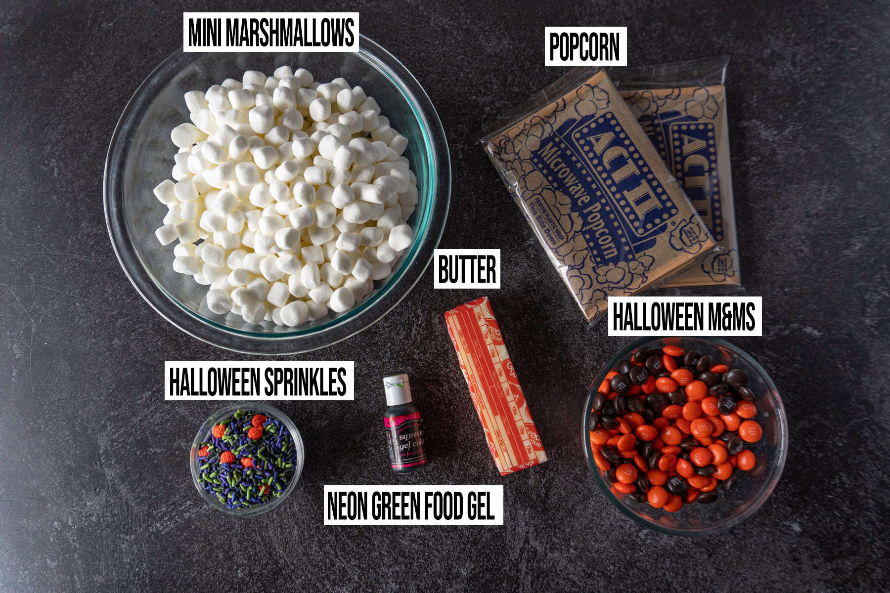 Halloween Popcorn Balls ingredients in individual bowls and labeled.