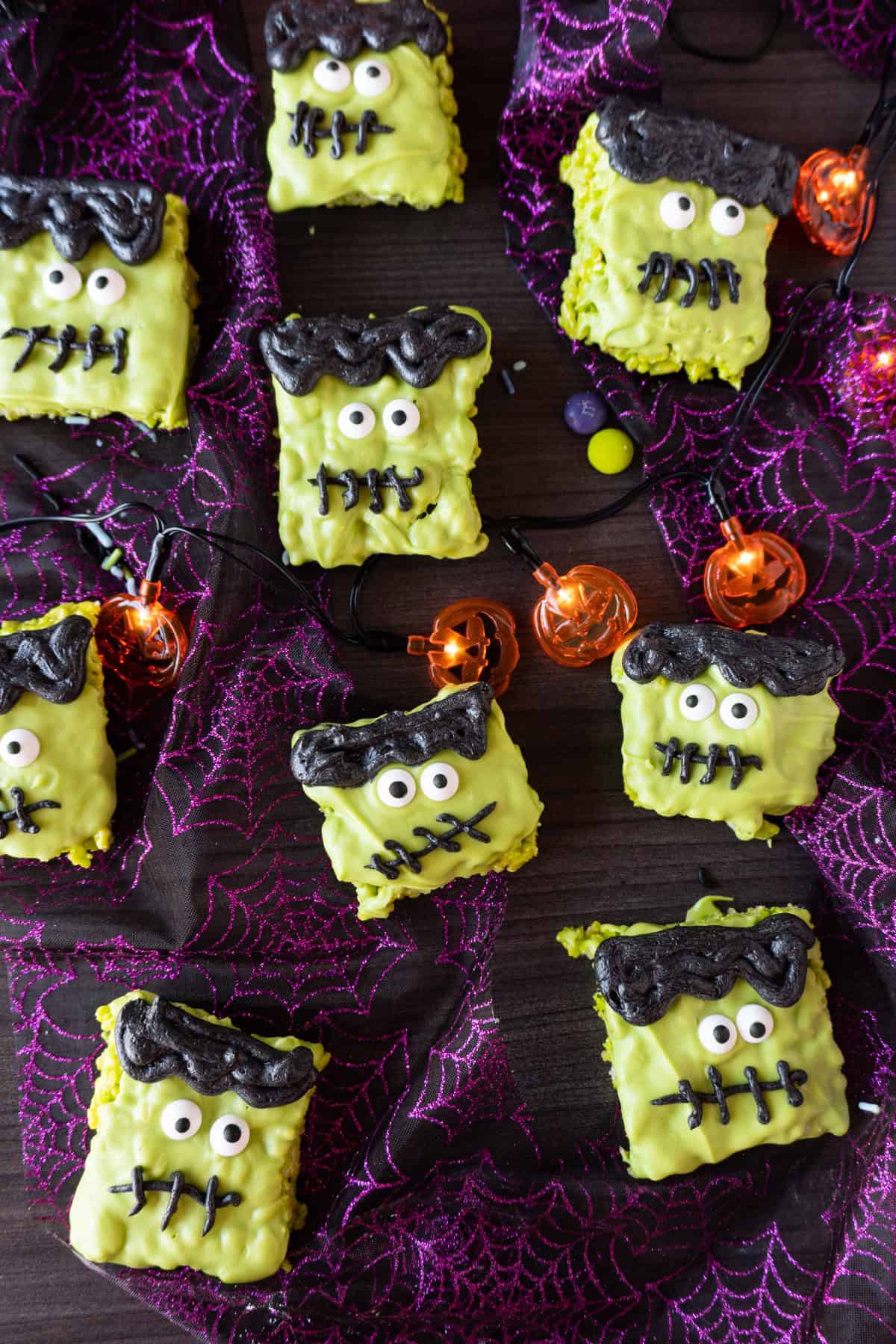 Frankenstein's Monster Rice Krispies Treats on spiderweb ribbon and surrounded by jack o' lantern lights.